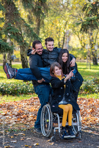 Konstfotografi Young disabled woman in a wheelchair taking selfi with friends in a park
