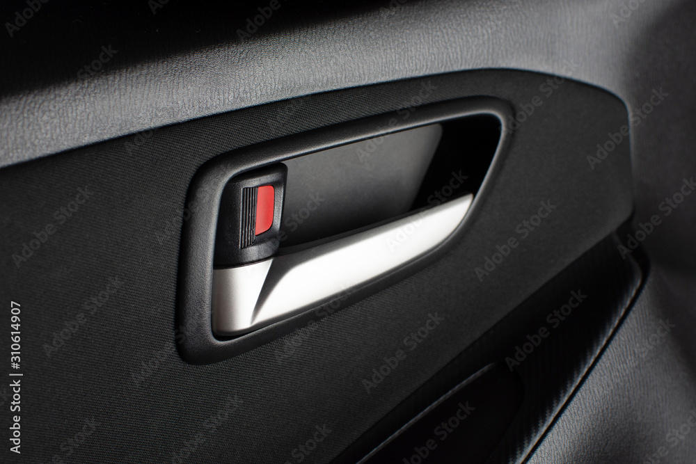 Car door lock / unlock button and metallic handle on the car door panel.