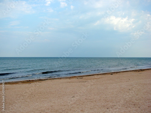 Panorama of the coast of the Azov Sea on a background of cloudy evening sky at sunset.