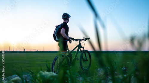 Cyclist on green meadows on a summer evening under sunset. Fitness concept. photo