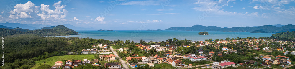 Aerial view panorama of Jabaquara, Paraty with buildings, Bay Carioca, mountains, islands and blue sky with clouds, Brazil