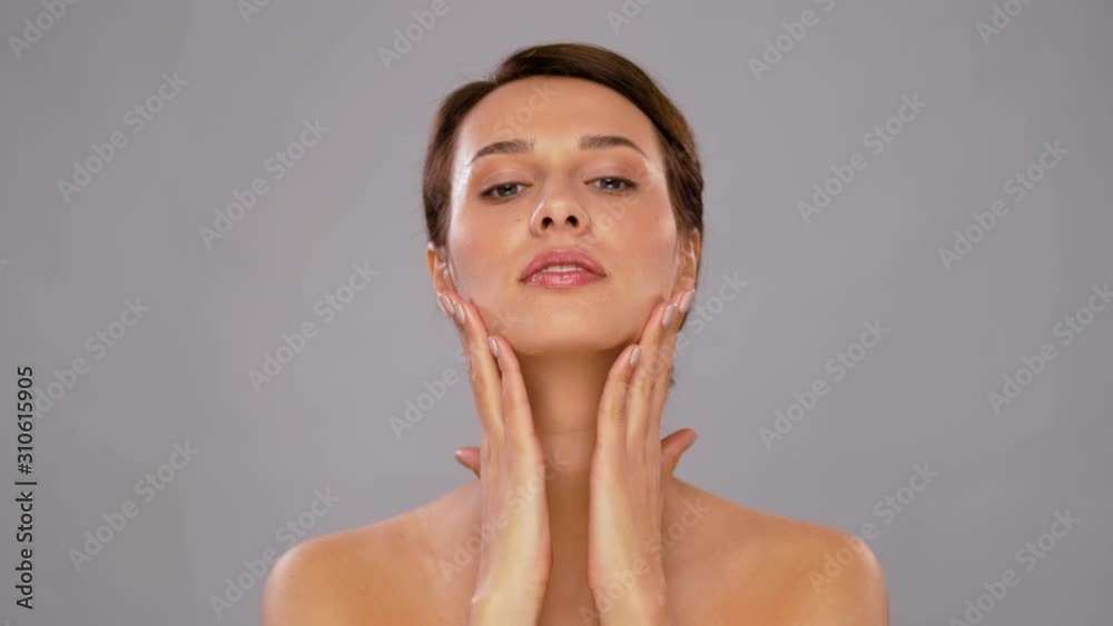 beauty, bodycare and people concept - beautiful young woman touching her face over grey background beauty, bodycare and people concept - beautiful young woman touching her face over grey background