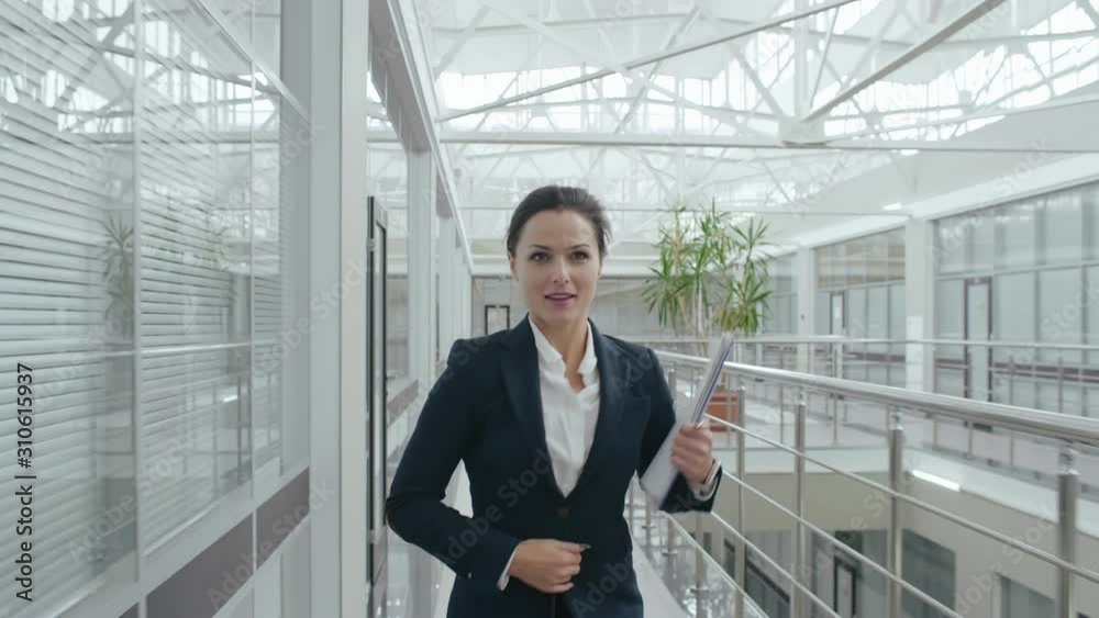Young attractive brunette businesswoman or female student in hurry busy, woman running late for work to meeting. Caucasian business lady in formal suit runs with documents papers in hands Young attractive brunette businesswoman or female student in hurry busy, woman running late for work to meeting. Caucasian business lady in formal suit runs with documents papers in hands