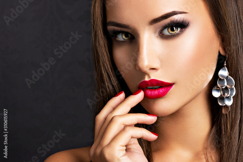 Fototapeta seductive woman with dark brown eye makeup and bright red lips and nails