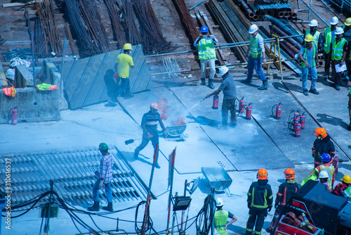 Construction workers wearing helmets at a construction site learning fire fighting skills