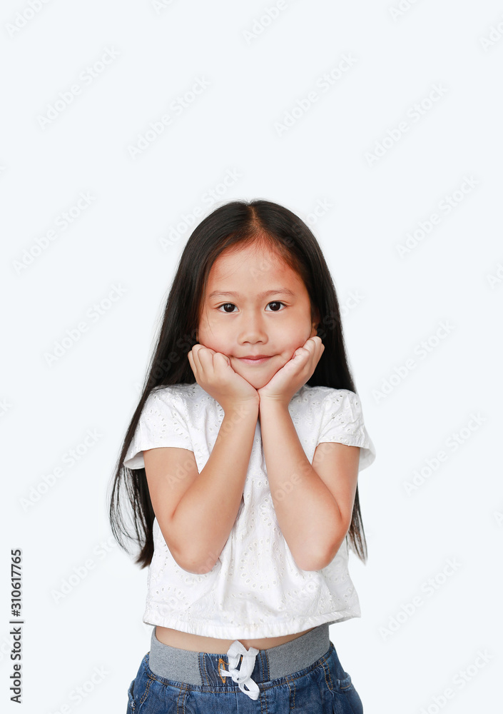 Happy little asian child girl keeps both hands on cheeks over white background with looking at camera. Charming and positive looking. Expresses pleasant emotions. Happy little asian child girl keeps both hands on cheeks over white background with looking at camera. Charming and positive looking. Expresses pleasant emotions.