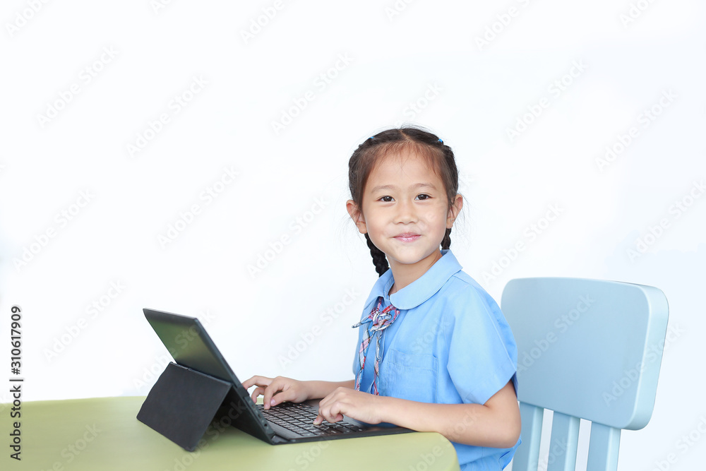 Happy little Asian girl using Laptop computer to do homework on desk over white background. Happy little Asian girl using Laptop computer to do homework on desk over white background.