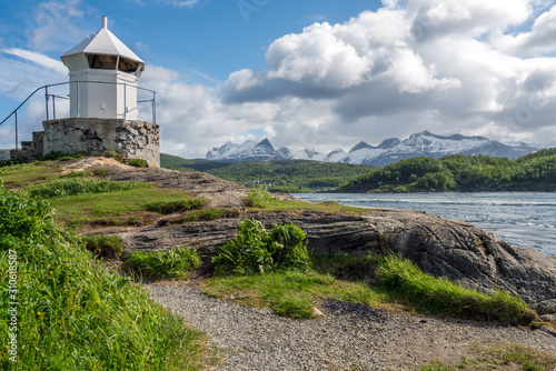 Saltstraumen river in Bodo in Northern Norway. Snow covered mountains in the background and blue cloudy sky, lighthouse in the foreground. Traveling and holiday concept. photo