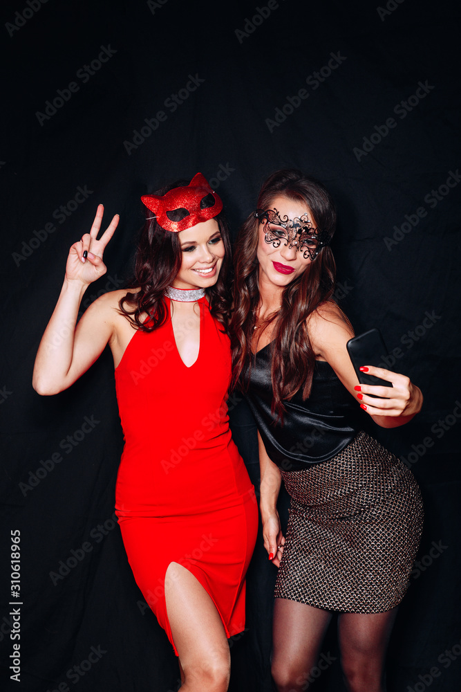 two young party women smiling taking selfie photo on mobile phone over black background two young party women smiling taking selfie photo on mobile phone over black background