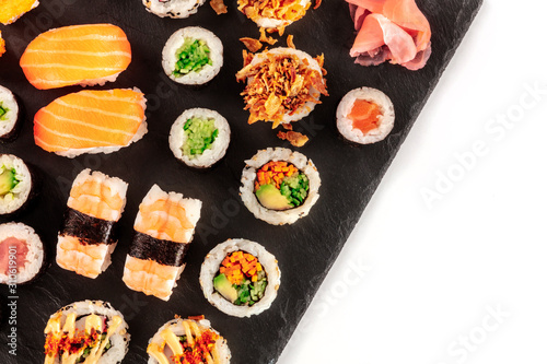 Large sushi set, close-up overhead shot on a white background with a place for text. An assortment of maki, nigiri and rolls