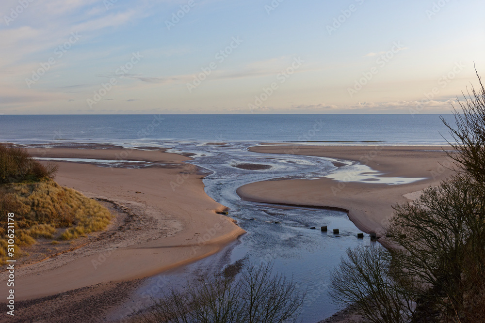 The mouth of the Lunan Water running over the beach at Lunan Bay and into the North Sea on a cold December morning.