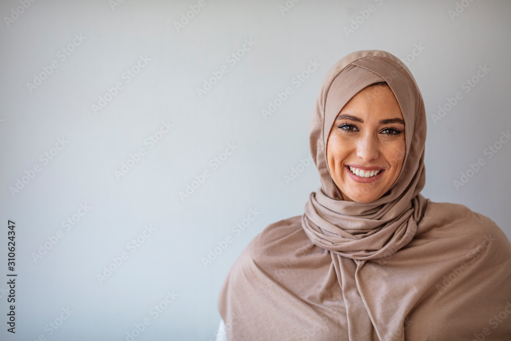 Young asian muslim woman in head scarf smile with arms crossed. Portrait of young muslim woman wearing hijab head scarf at gray background. Portrait of beautiful Muslim woman on grey background Young asian muslim woman in head scarf smile with arms crossed. Portrait of young muslim woman wearing hijab head scarf at gray background. Portrait of beautiful Muslim woman on grey background