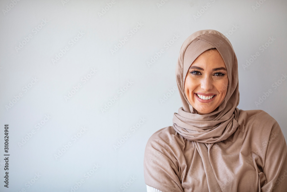 Portrait of pretty young asian muslim woman in head scarf smile. Portrait closeup of muslim prayer woman 20s in hijab smiling isolated over gray background. Portrait of pretty young asian muslim woman in head scarf smile. Portrait closeup of muslim prayer woman 20s in hijab smiling isolated over gray background.