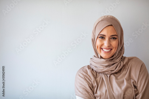 Portrait of pretty young asian muslim woman in head scarf smile. Portrait closeup of muslim prayer woman 20s in hijab smiling isolated over gray background. photo