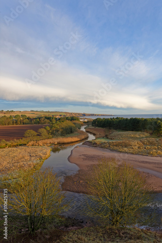 The Lunan River gently winding itself through the hills and farmland behind Lunan Bay on the east coast of Scotland in December.