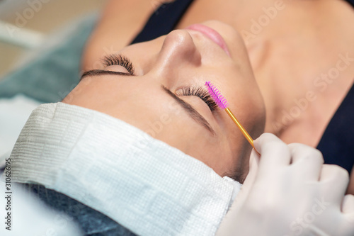 Young woman receiving eyelash extension in a beauty salon  Eyelash extension procedure.