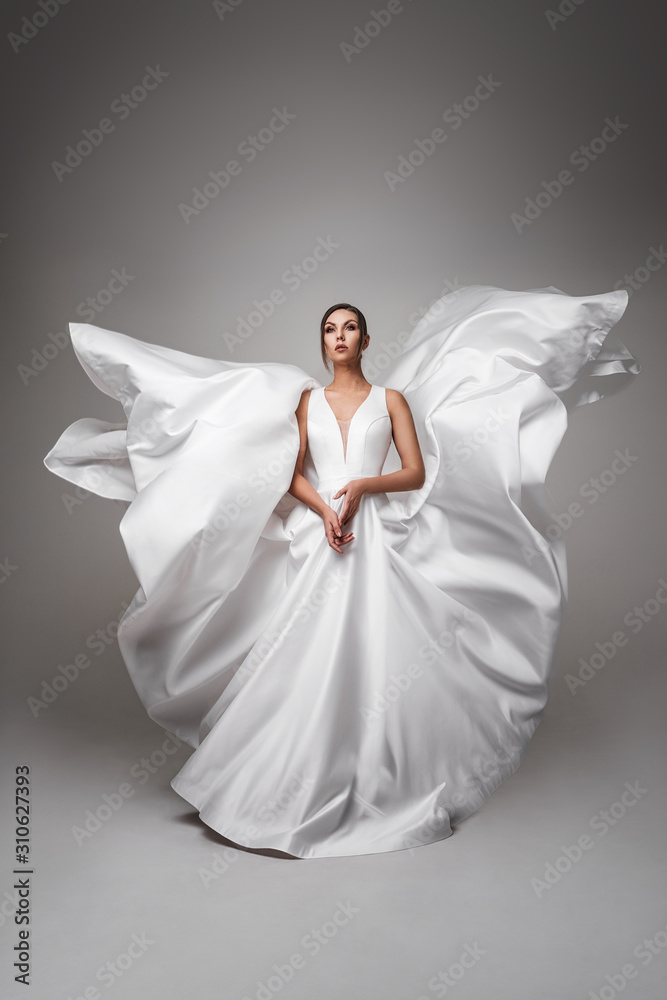 Pretty dark-haired girl in a flying wedding dress. White dress fluttering in the wind. Fashion Wedding Photography Concept Pretty dark-haired girl in a flying wedding dress. White dress fluttering in the wind. Fashion Wedding Photography Concept
