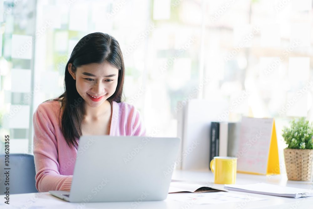 Confident happiness young woman working on laptop or notebook in her office. Beautiful Freelancer Woman working online at her home. Beauty Asian business woman concept. Confident happiness young woman working on laptop or notebook in her office. Beautiful Freelancer Woman working online at her home. Beauty Asian business woman concept.
