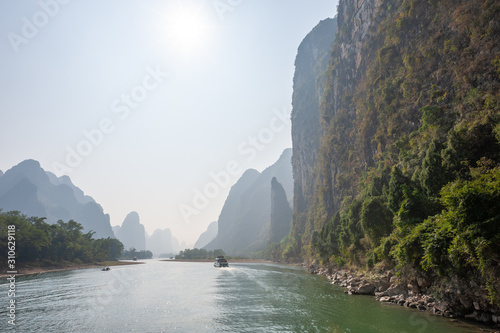 Boat on Li river cruise and karst formation mountain landscape in the fog between Guiling and Yangshuo, Guangxi province, China