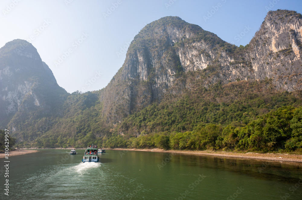 Boat on Li river cruise and karst formation mountain landscape in the fog between Guiling and Yangshuo, Guangxi province, China Boat on Li river cruise and karst formation mountain landscape in the fog between Guiling and Yangshuo, Guangxi province, China
