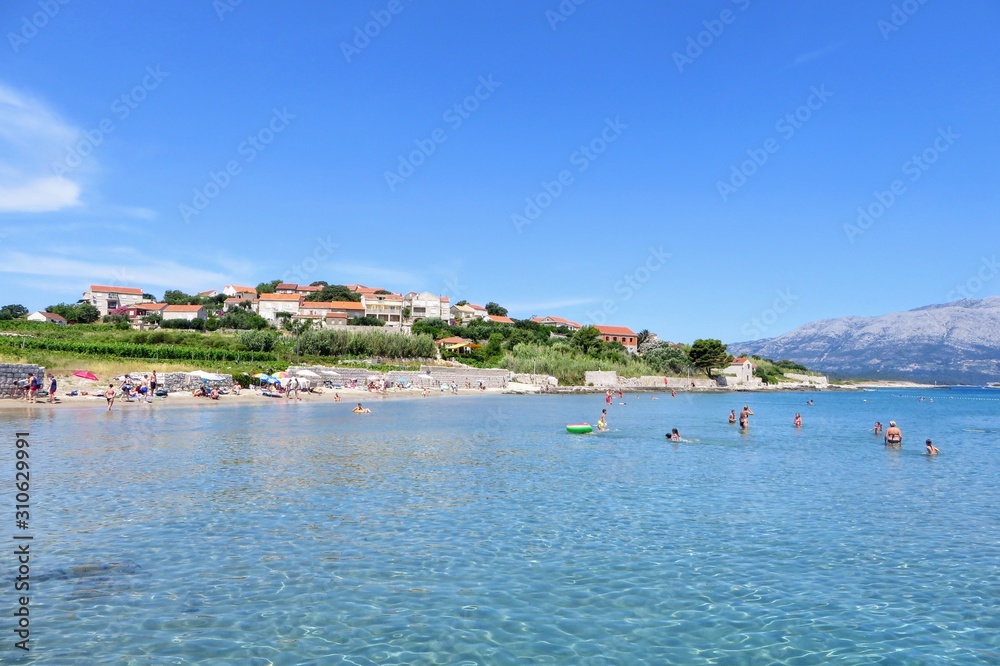Fototapeta premium Locals and tourists enjoying a beautiful summer day along the sandy beaches of Lumbarda Beach on Korcula Island, Croatia