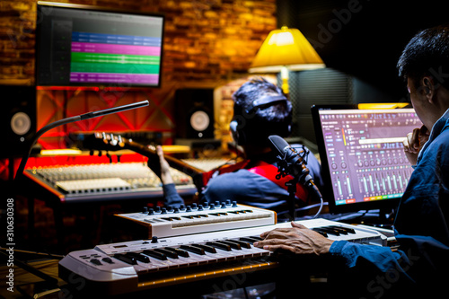 professional male music producer, composer working with guitarist in recording studio. music production concept