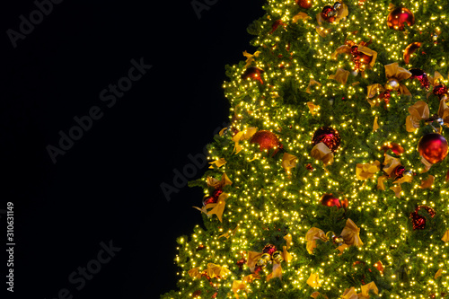 Lighting bulb and decorative pine tree in Merry Christmas and Happy New Year at the night for abstract background texture with black copy space text