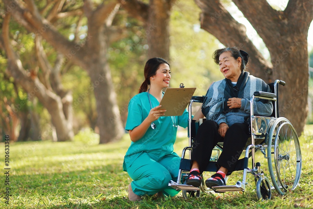 Grandmother in wheelchair taking with nurse in hospital park. Grandmother in wheelchair taking with nurse in hospital park.
