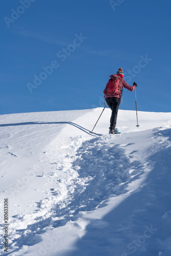 active senior woman snowshoeing from Prato Piazzo up to the Monte Specie in the three oeaks Dolomites area near village of Innichen, South Tyrol, Italy