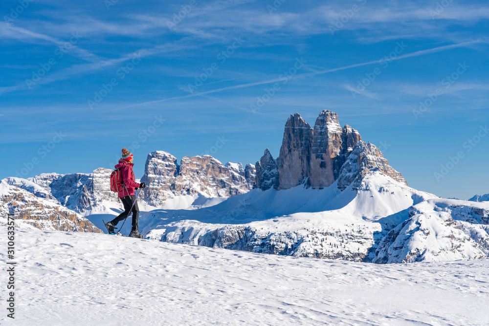 active senior woman snowshoeing  under the famous Three Peaks, Dolomites  near village of Toblach, South Tyrol, Italy