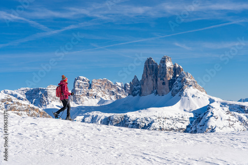 active senior woman snowshoeing  under the famous Three Peaks, Dolomites  near village of Toblach, South Tyrol, Italy photo