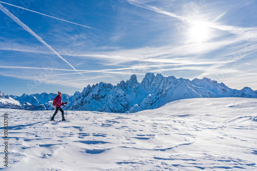 active senior woman snowshoeing under the famous Three Peaks from Prato Piazzo up to the Monte Specie in the three oeaks Dolomites area near village of Innichen, South Tyrol, Italy photo