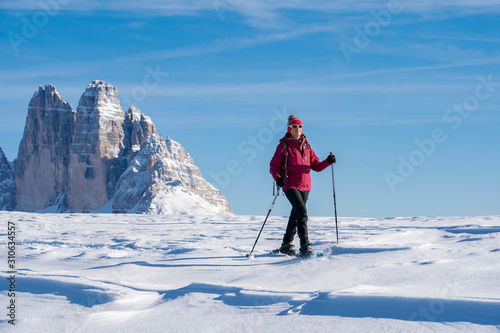 active senior woman snowshoeing under the famous Three Peaks from Prato Piazzo up to the Monte Specie in the three oeaks Dolomites area near village of Innichen, South Tyrol, Italy