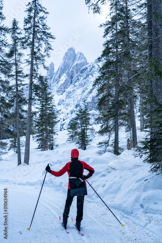 active senior woman on her cross country skis on ski track in the Fischlein Valley, Three peak Dolomites, South Tyrol, Italy photo