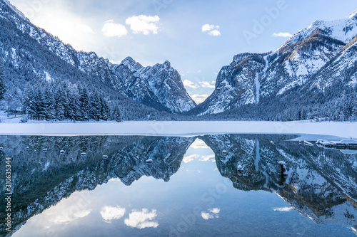 landscape photography on cold winter morning at sunrise at partly frozen Lago Dobbiaco, Dolomites, Three Peaks Dolomites, South Tyrol, Italy