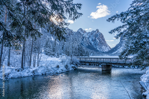 landscape photography on cold winter morning at sunrise at partly frozen Lago Dobbiaco, Dolomites, Three Peaks Dolomites, South Tyrol, Italy photo