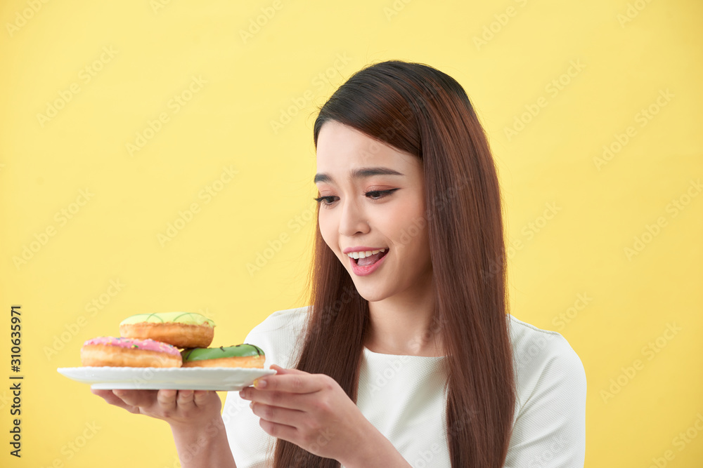 Beautiful young woman smiling holding a plate full of delicious color donuts