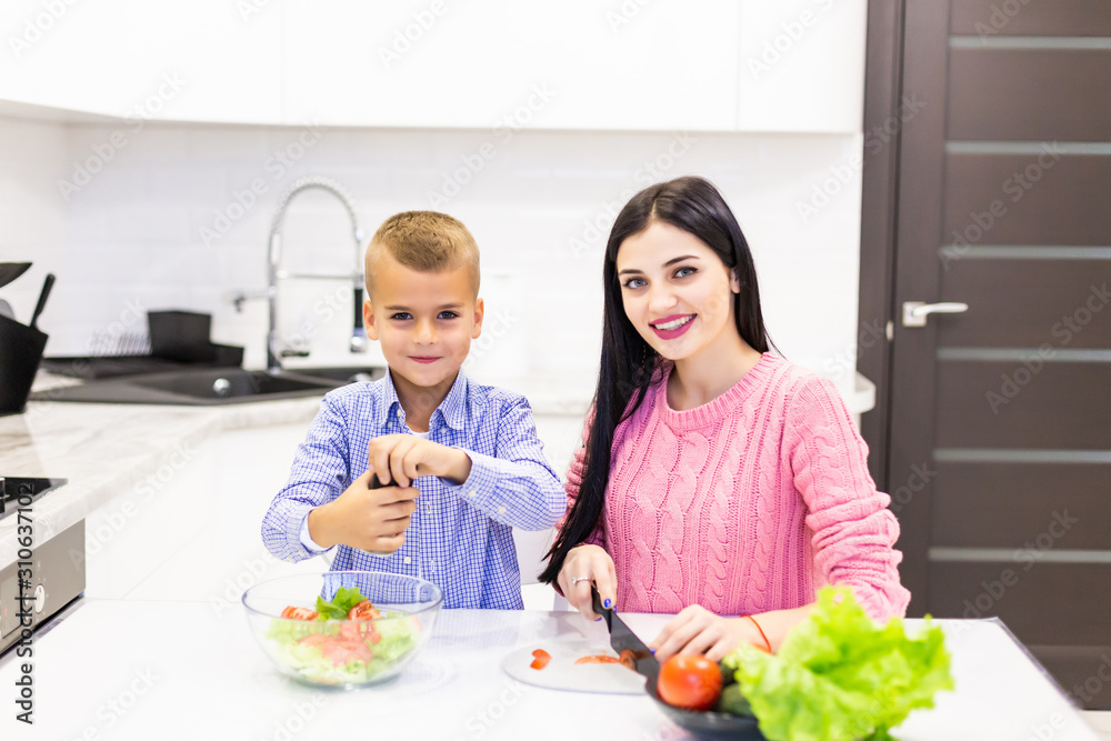 Mother and son cook salad in the kitchen at home
