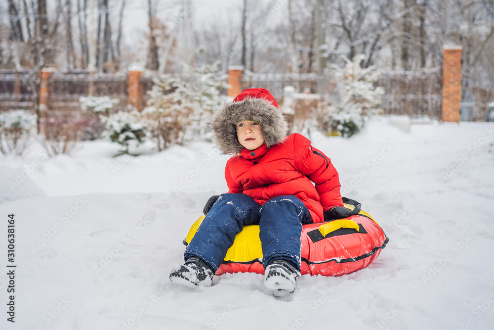 Child having fun on snow tube. Boy is riding a tubing. Winter fun for children Child having fun on snow tube. Boy is riding a tubing. Winter fun for children
