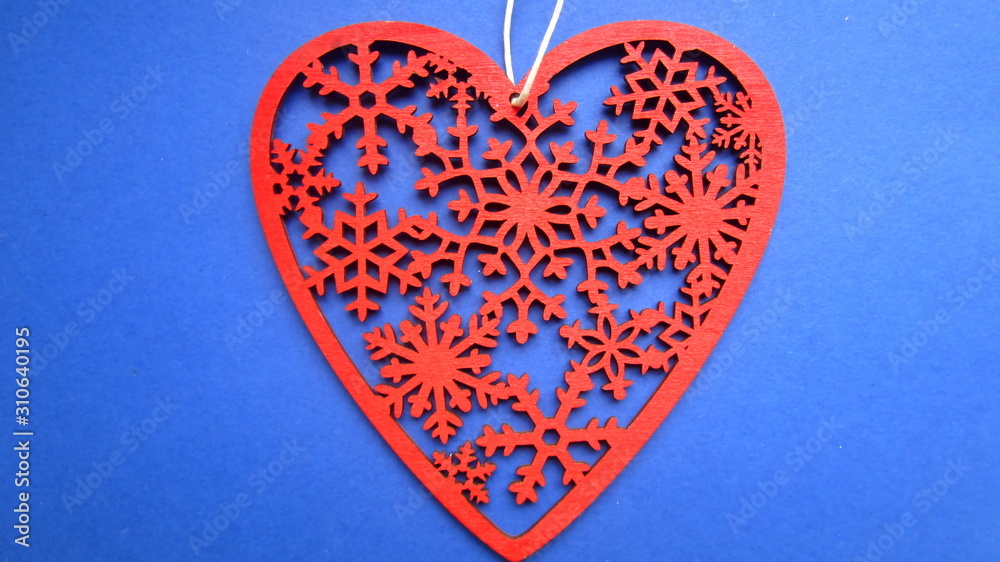 Cut out in wood a red ornamental heart on a string with a bead on a blue background. Flat lay.  Creative gift idea