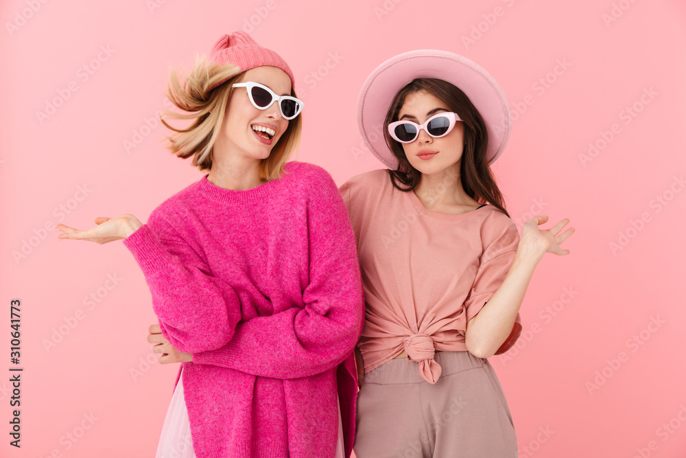 Image of two cheerful women posing at camera in stylish sunglasses