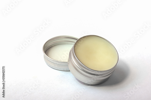 Lip balm in the round metallic tins on the white background photo