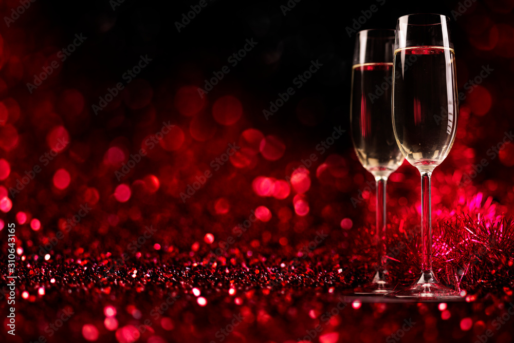 Two champagne glasses on sparkling red bokeh background. Valentine's day dinner invitation. Christmas and new year holiday party.