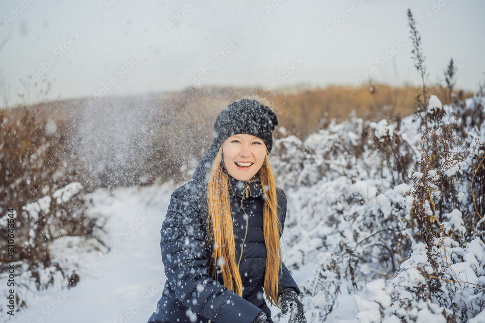 winter girl throwing snowball at camera smiling happy having fun outdoors on snowing winter day playing in snow. Cute playful young woman outdoor enjoying first snow winter girl throwing snowball at camera smiling happy having fun outdoors on snowing winter day playing in snow. Cute playful young woman outdoor enjoying first snow