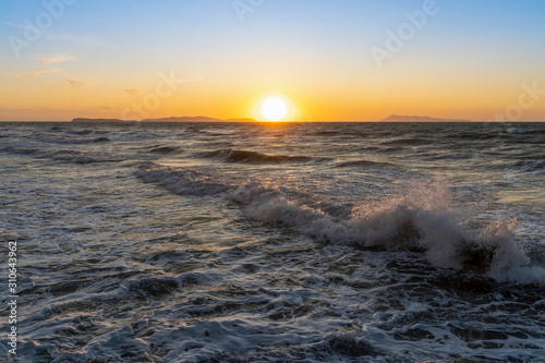 Bright sea sunset.. White foamy dynamic waves rolling and crashing in sunset illumination. Never ending beauty of nature. Logas Beach  Sidari  Corfu  Greece  Europa.Bright sea sunset.