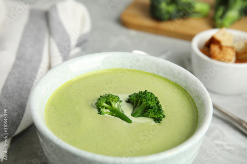 Bowl of delicious broccoli cream soup on table, closeup