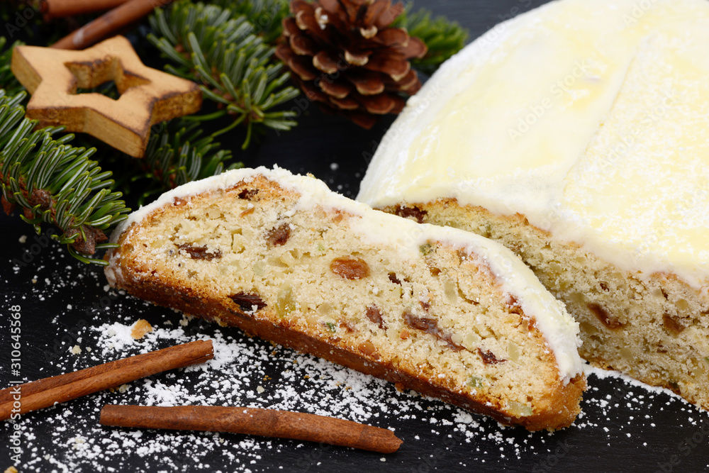 christmas stollen with fir branch, pine cone, stars and cinnemon sticks lying on black shale at christmas time christmas stollen with fir branch, pine cone, stars and cinnemon sticks lying on black shale at christmas time