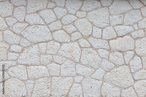 the texture of the wall is made up of pieces of different shapes of natural white stone. White brick wall, background, texture. 