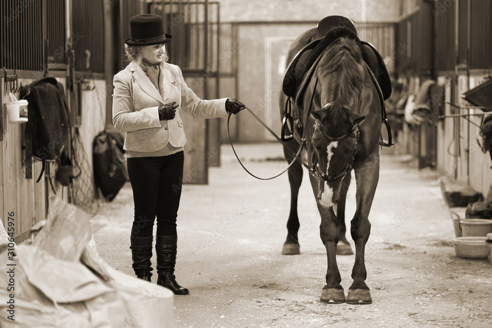 A 50 year old woman rides a horse. Walking with a horse. He is engaged