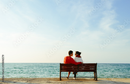 young couple looking at each other on bench by the Aegean sea
